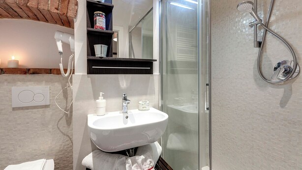 Une salle de bain avec une douche à parois de verre, un lavabo blanc et un porte-serviettes.