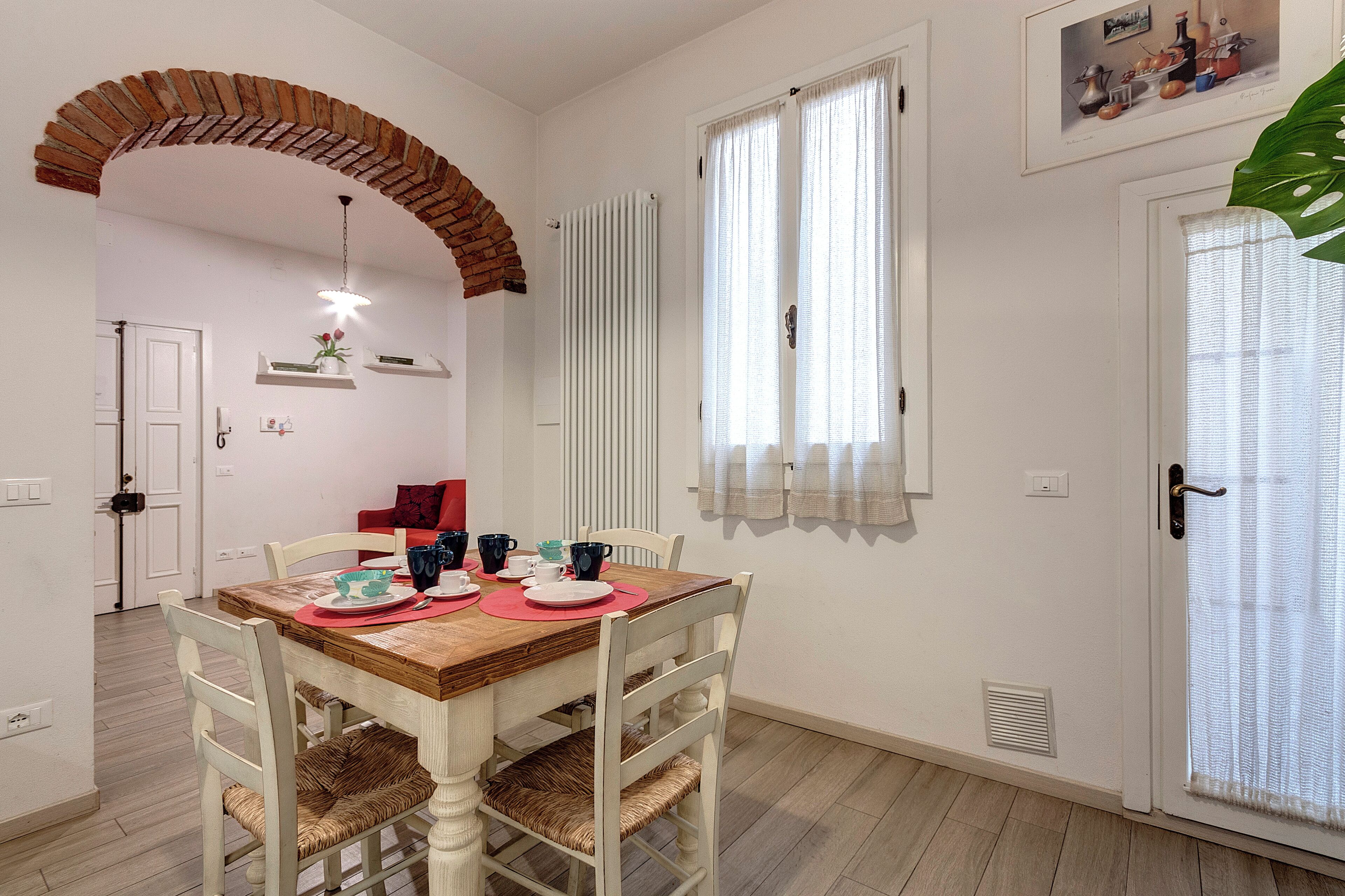 A dining area with a wooden table, white chairs, and a brick archway.