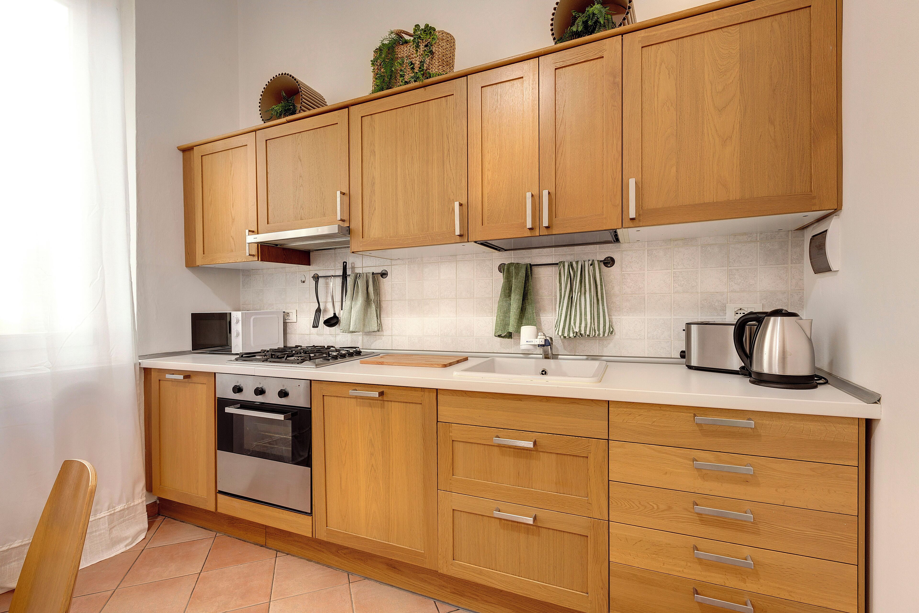 A kitchen with wooden cabinets, a stove, a microwave, and a sink.