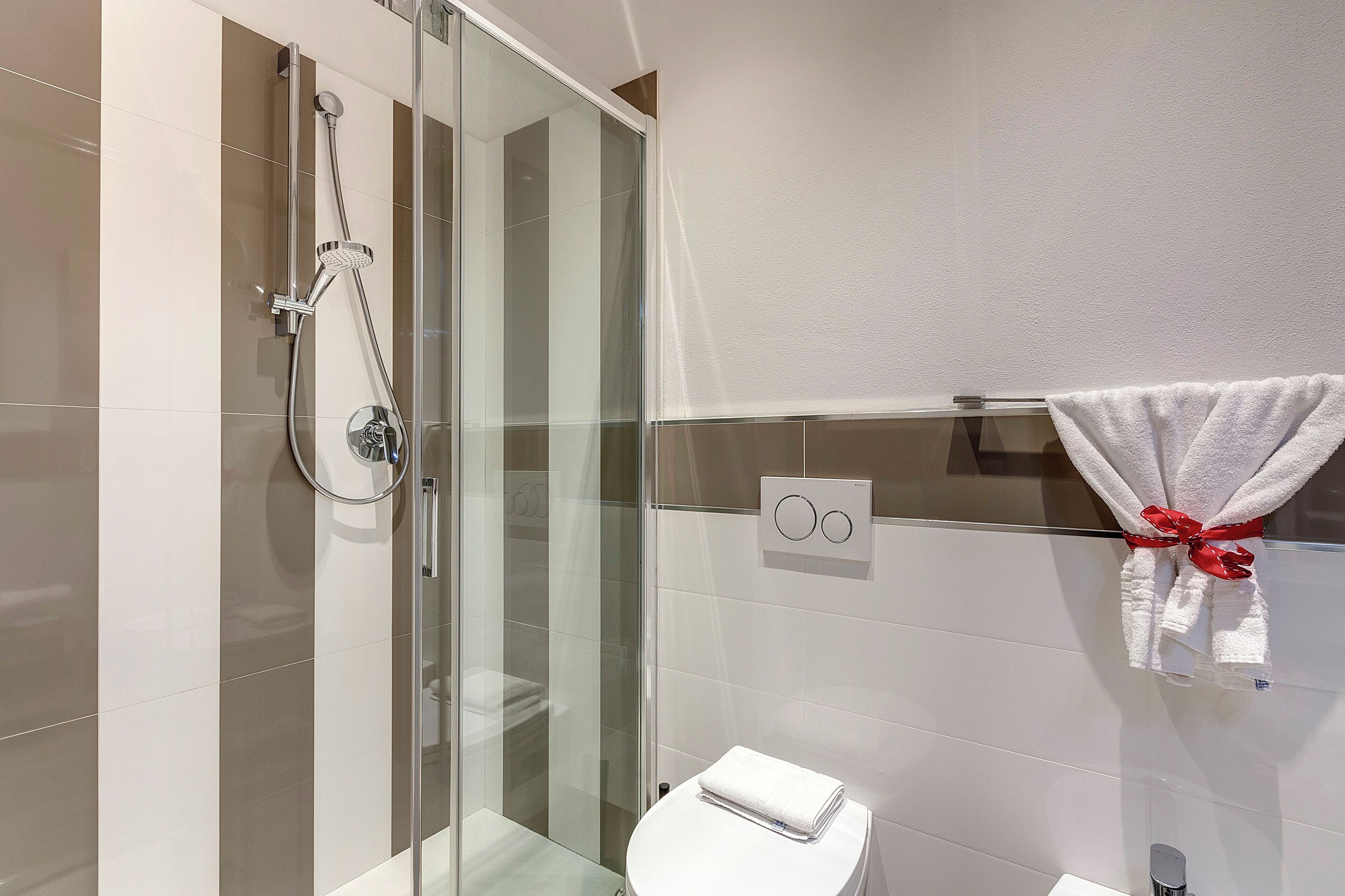 A modern bathroom with a glass-enclosed shower, a white toilet, and a towel rack with a towel.
