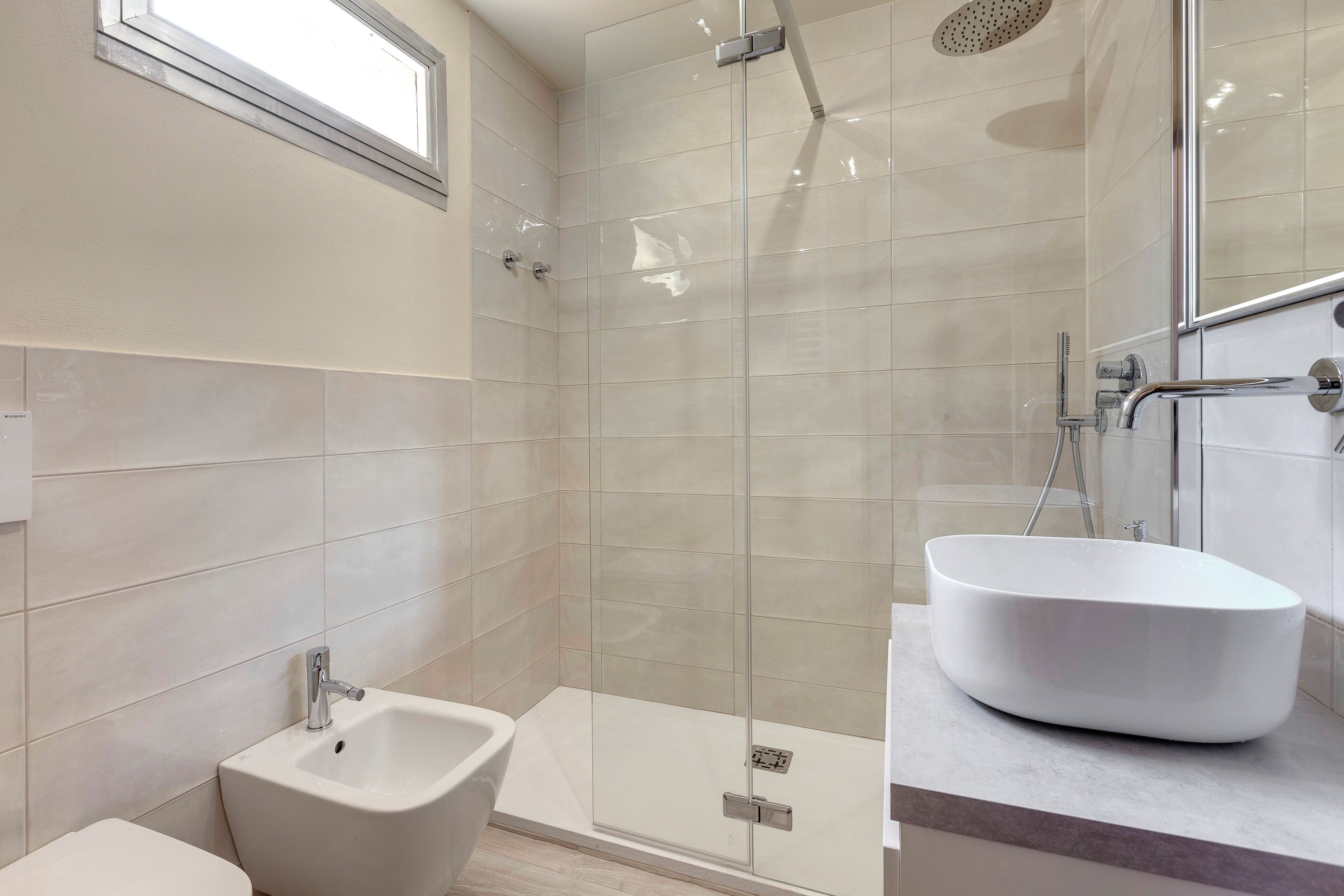 Ein modernes Badezimmer mit einer Glaskabine, einem freistehenden Waschbecken und einem Bidet.
