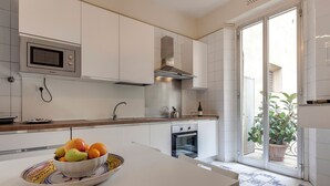 Una cocina moderna con armarios blancos, un microondas integrado, un horno y un tazón de fruta en la encimera.