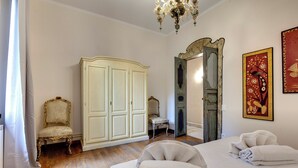 Habitación de hotel con una cama grande, un armario, una silla y una araña.