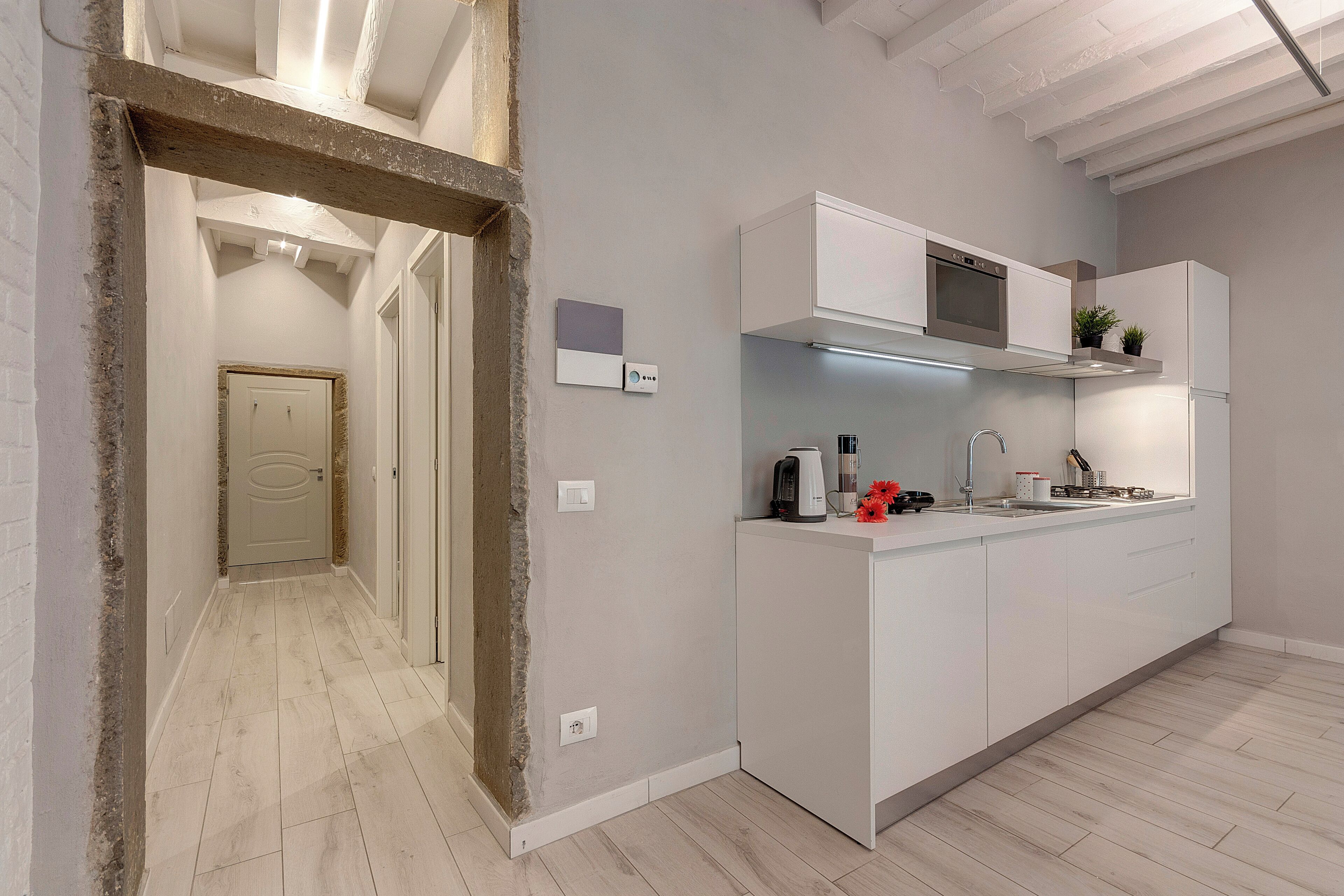 A modern kitchen with white cabinetry, a built-in oven, and a stainless steel sink.