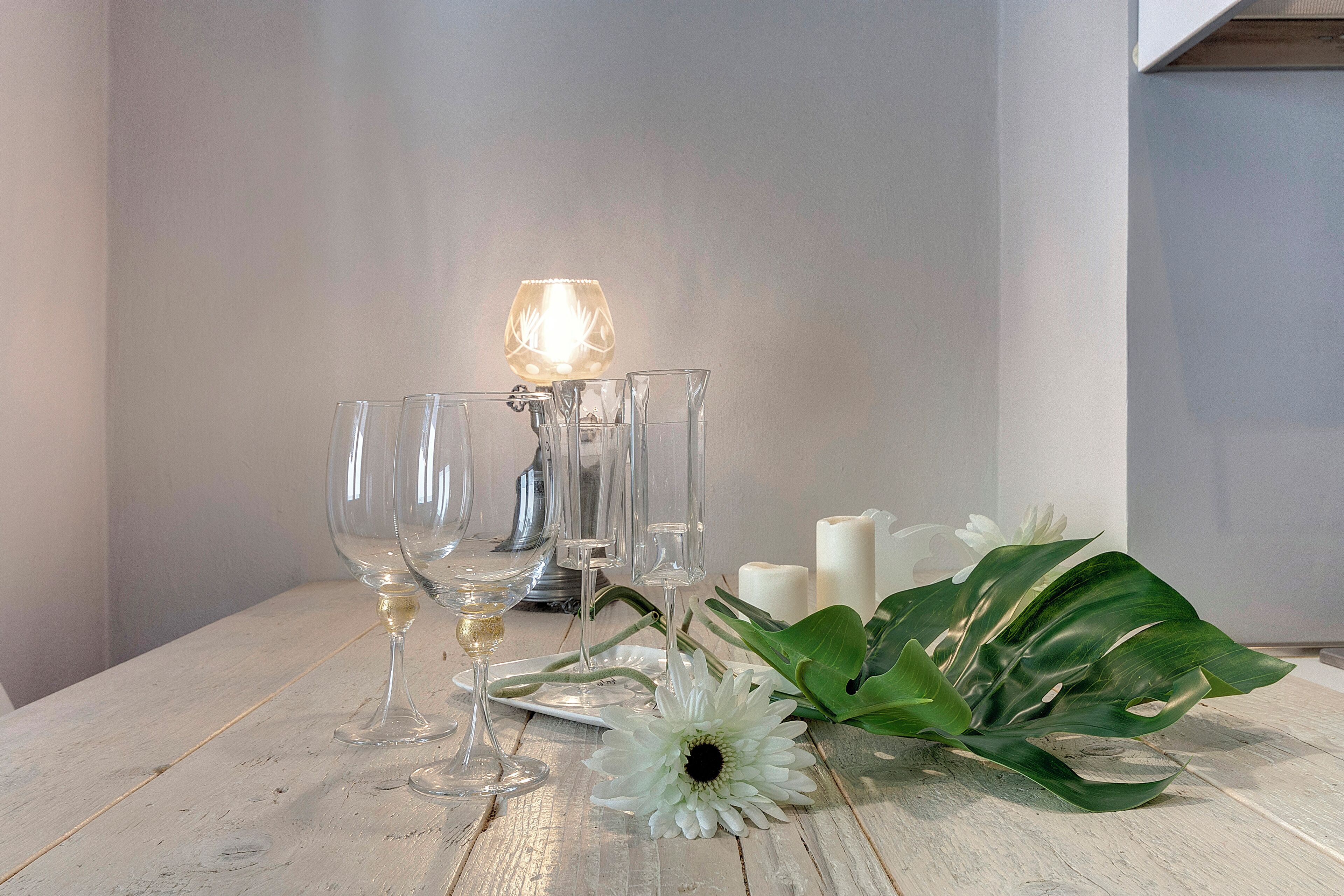 A table with wine glasses, a candle, and a flower.