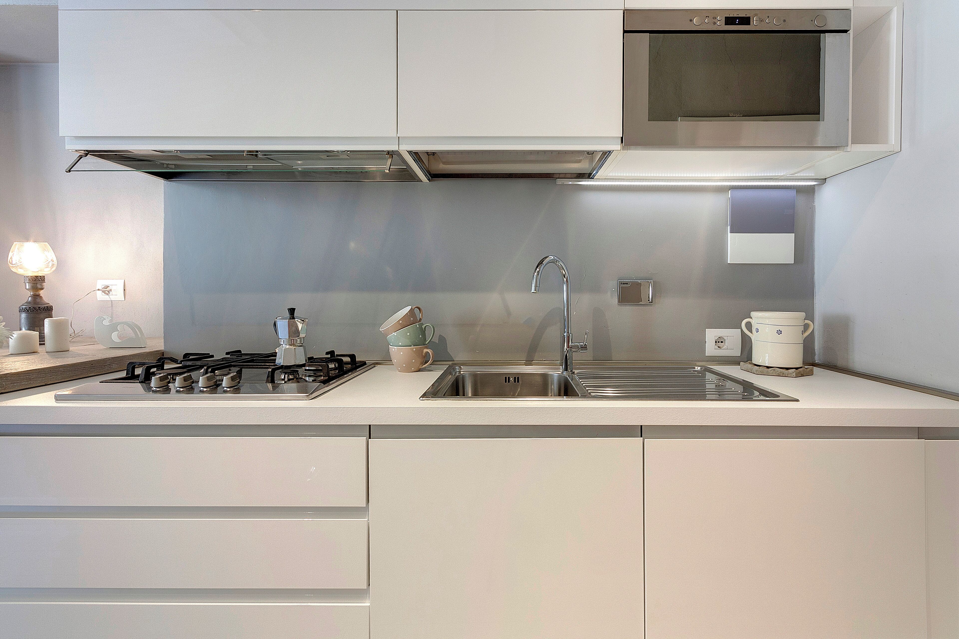 Une cuisine moderne dotée d’un évier en acier inoxydable, d’une cuisinière à gaz et d’un four à micro-ondes placé au-dessus du plan de travail.