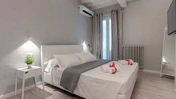 A modern bedroom with a bed, bedside tables, a small plant, and a radiator.