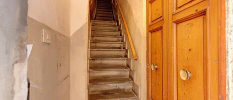 Un escalier étroit, avec des portes en bois sur le côté droit, mène à un palier.
