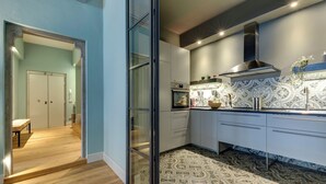 A modern kitchen with a patterned backsplash, stainless steel appliances, and a sliding glass door leading to a dining area. - Mamo Florence - Frida Luxury Apartment (Florence)