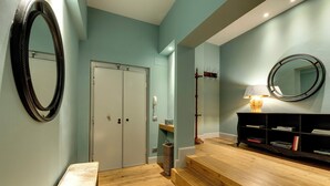A hallway with a wooden bench, a mirror, a door, a lamp, and a bookshelf. - Mamo Florence - Frida Luxury Apartment (Florence)
