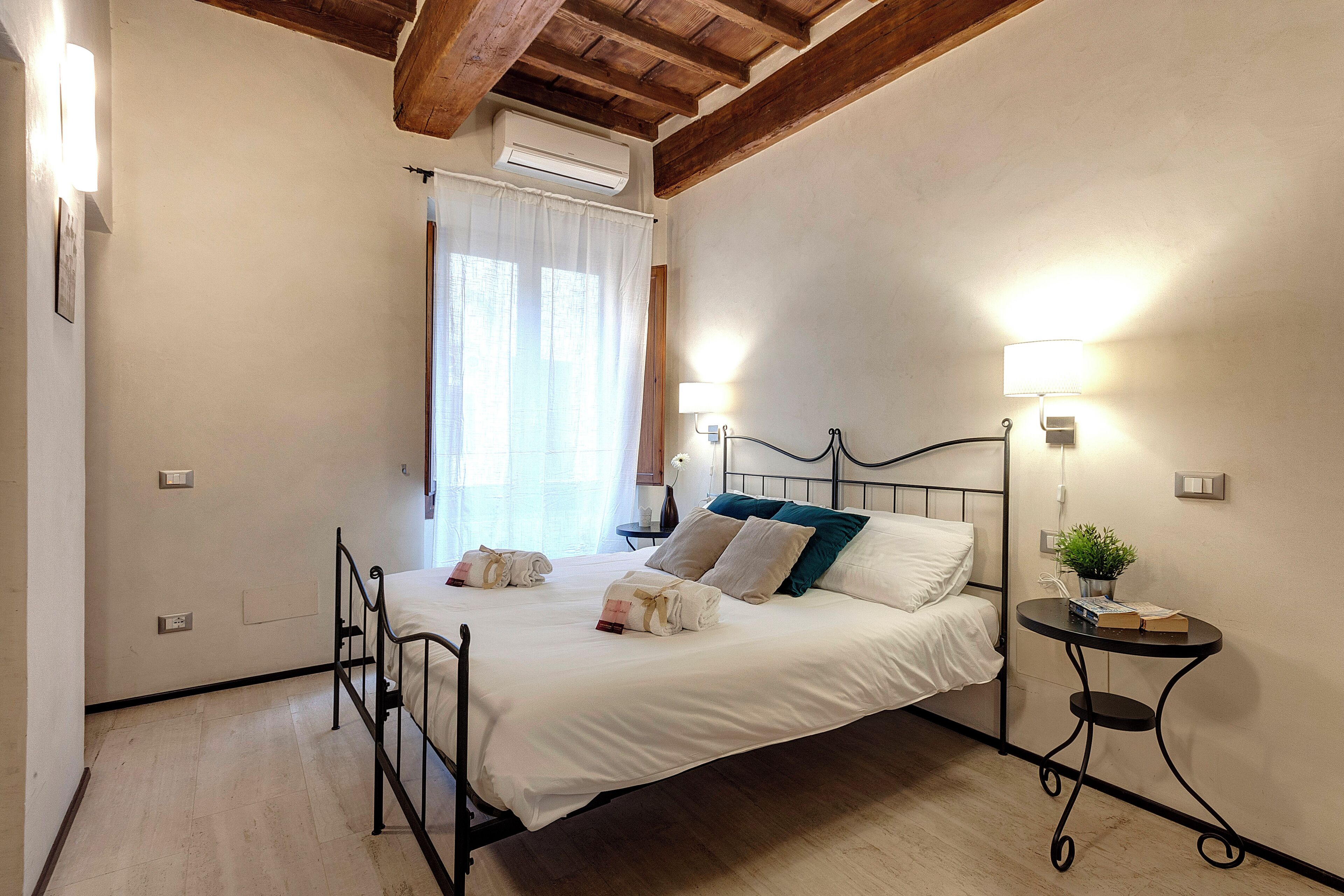 A bedroom with a bed, bedside tables, and a window with curtains.