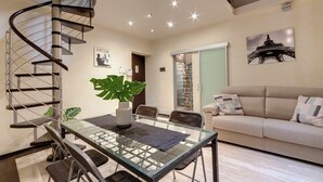 Uma sala de estar moderna com uma escada em espiral, uma mesa de jantar de vidro e um sofá.