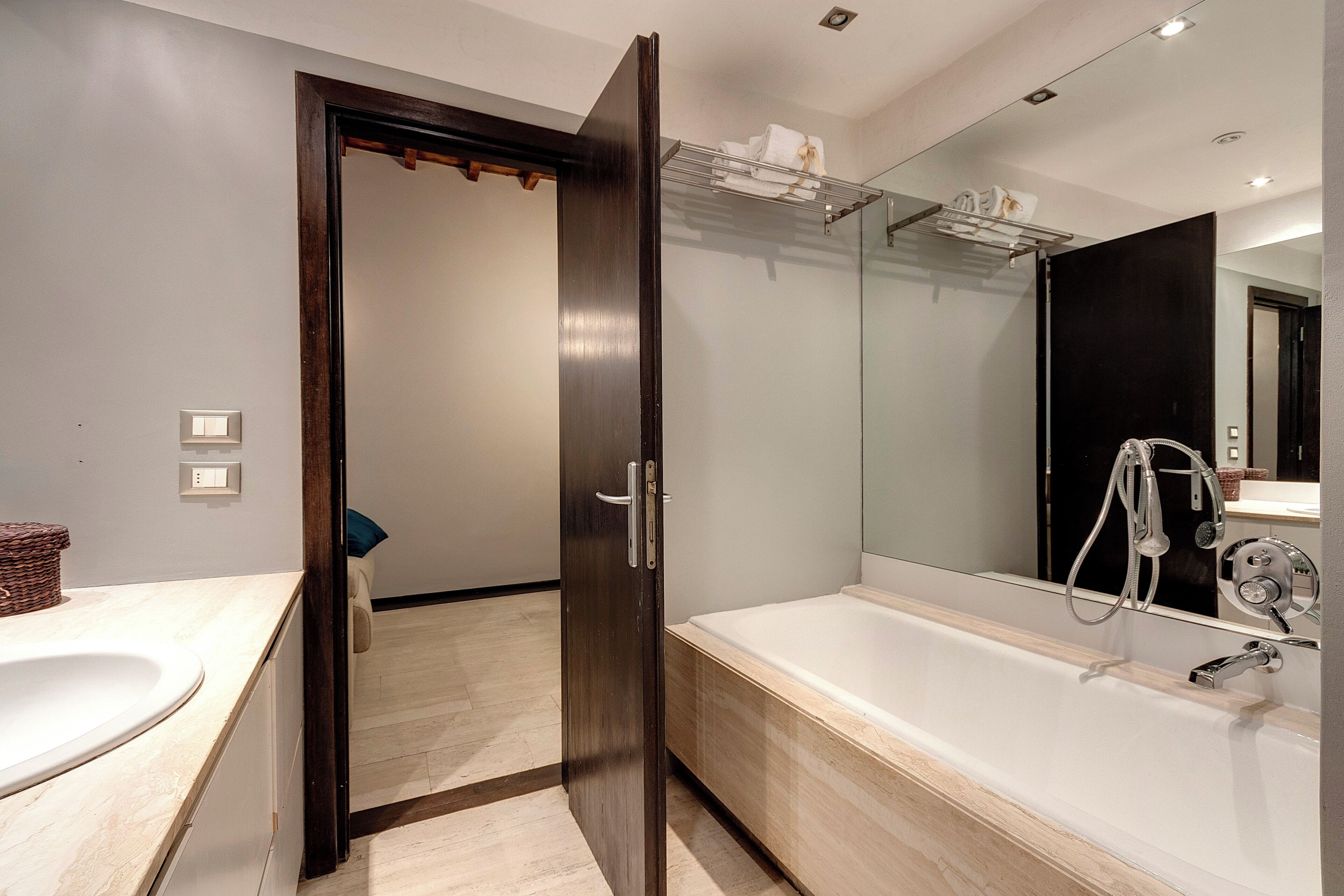 A modern bathroom with a large bathtub, a glass shower enclosure, and a wooden vanity.