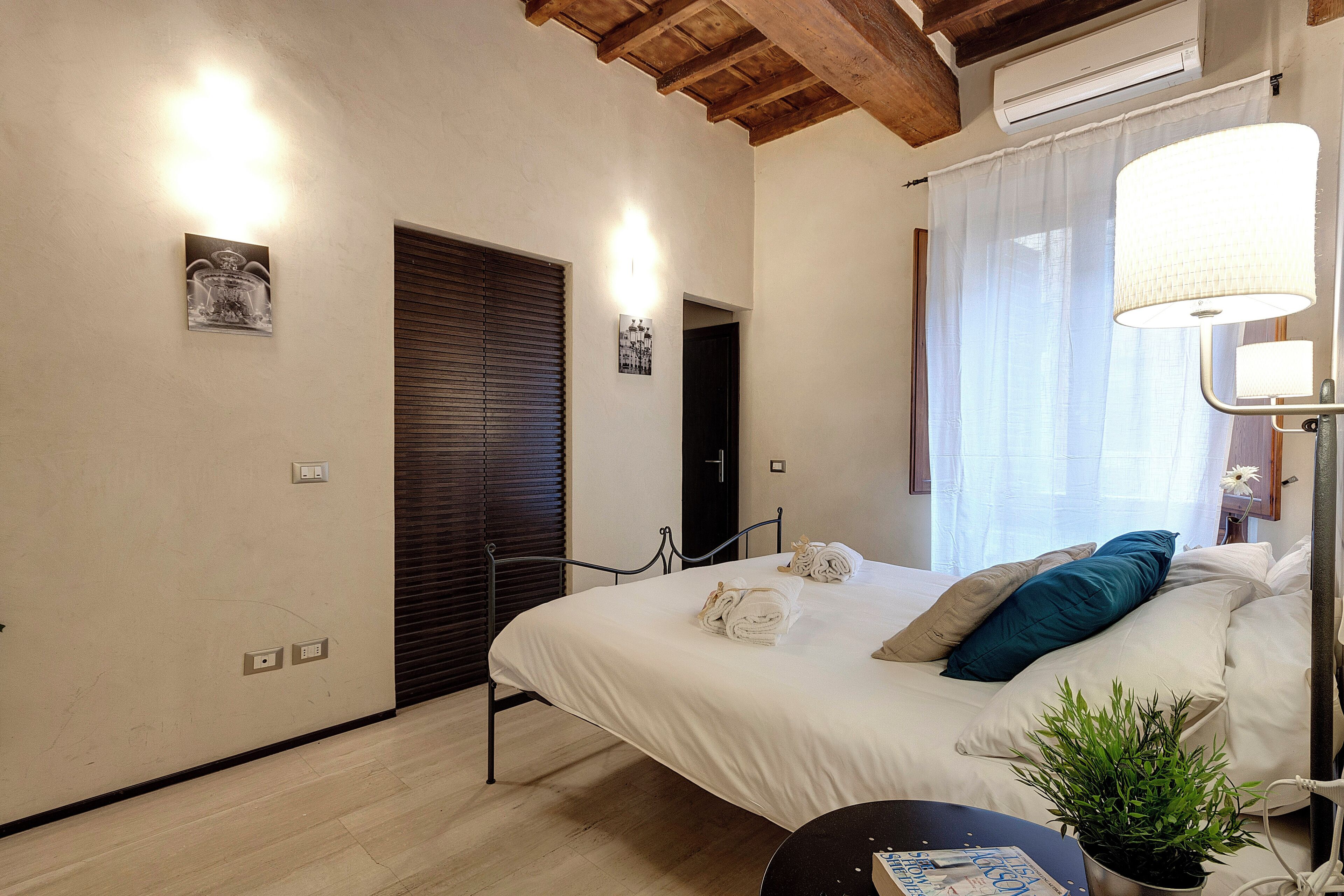 Une chambre à coucher avec un lit, une table de chevet, une lampe et une plante en pot.