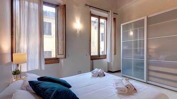 A hotel room with a bed, pillows, a lamp, and a window with curtains.