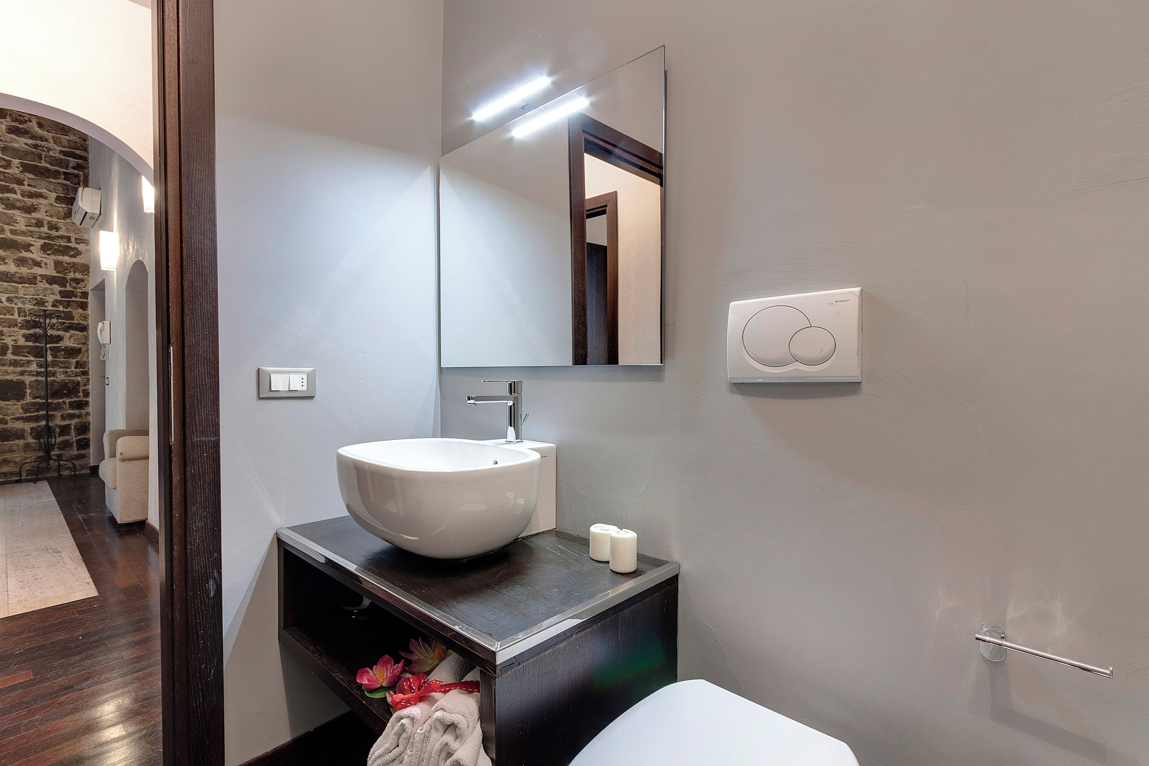 A bathroom with a white sink, dark wooden vanity, a large mirror, and a towel rack.