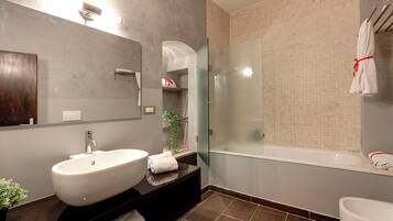 A modern bathroom with a large white sink, a glass-enclosed shower, and a bathtub.