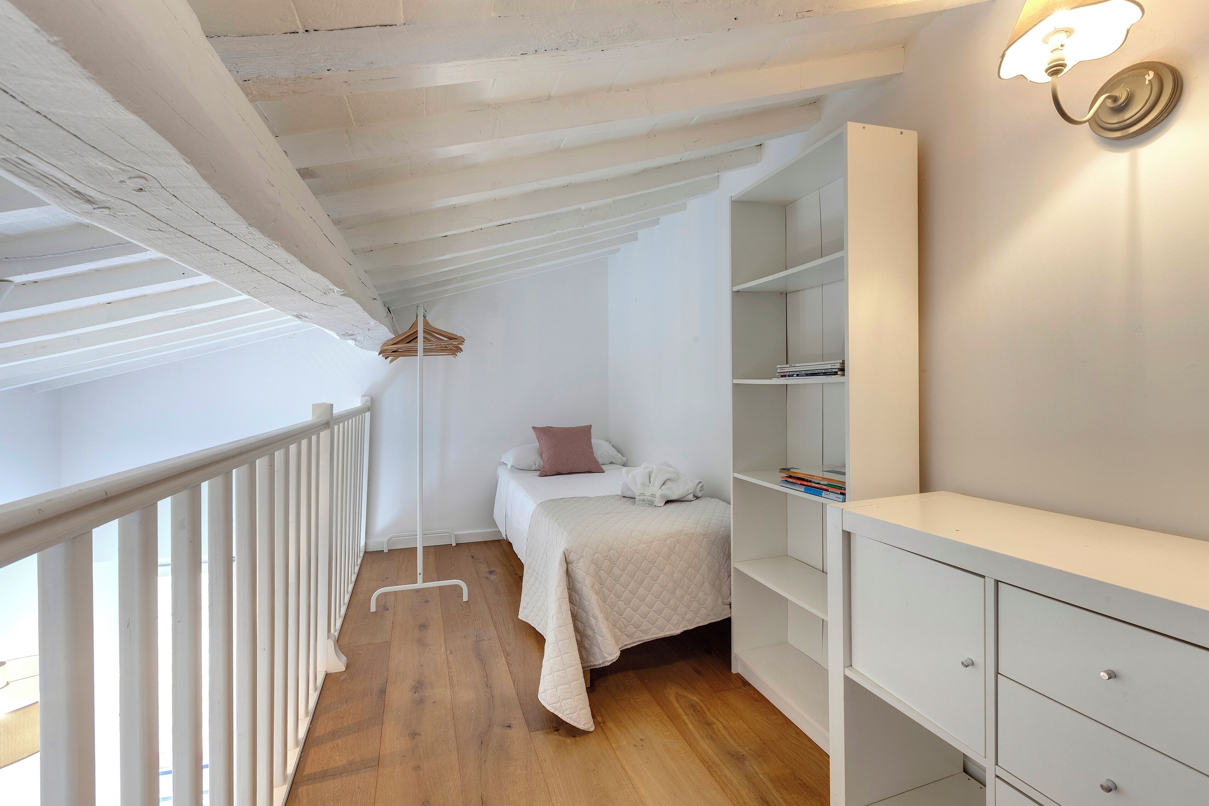 Une chambre à coucher comprenant un lit, des tables de chevet, une armoire et un luminaire suspendu.