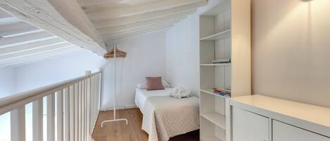 Une chambre à coucher comprenant un lit, des tables de chevet, une armoire et un luminaire suspendu.