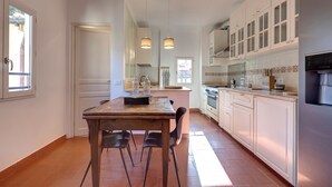 A modern kitchen with white cabinets, a central island, and a dining area with a wooden table and chairs.