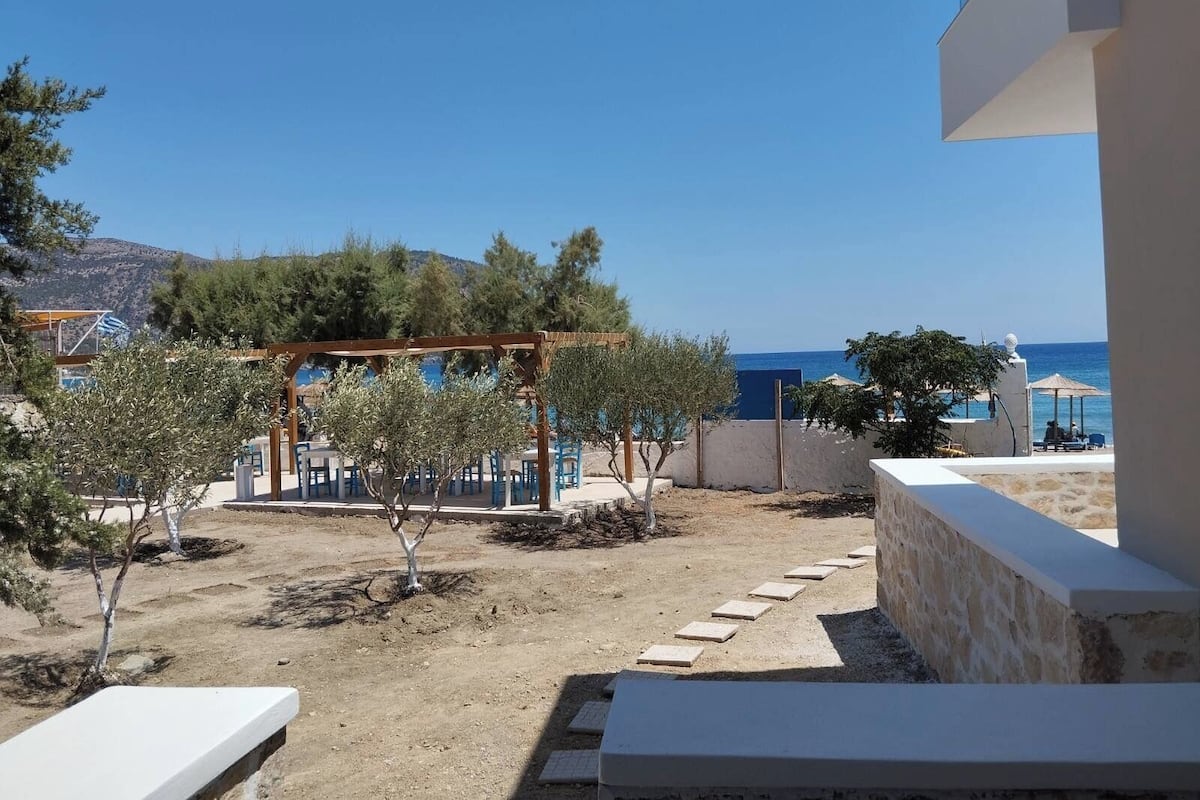 A terrace with outdoor seating, a pergola, and a view of the sea.