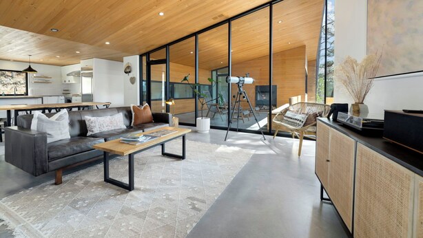 Een moderne woonkamer met een bank, salontafel en een groot raam met uitzicht op de omgeving.