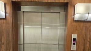 An elevator with a digital display and a control panel, surrounded by wooden paneling. - FLOWER1 ALMUGHRIZAT (Riyadh)