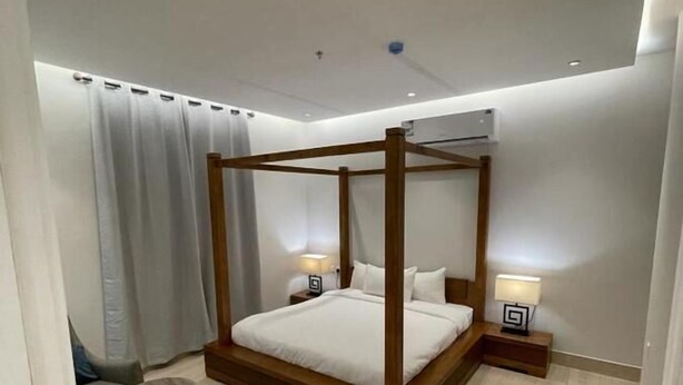 A modern bedroom with a four-poster bed, a small sofa, and two bedside tables with lamps. - FLOWER1 ALMUGHRIZAT (Riyadh)
