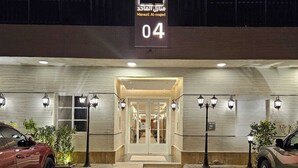 A hotel entrance with a sign indicating room number 04, a covered walkway, and two cars parked in front. - FLOWER1 ALMUGHRIZAT (Riyadh)