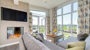 Una sala de estar moderna con chimenea, ventanas amplias y vistas al exterior.