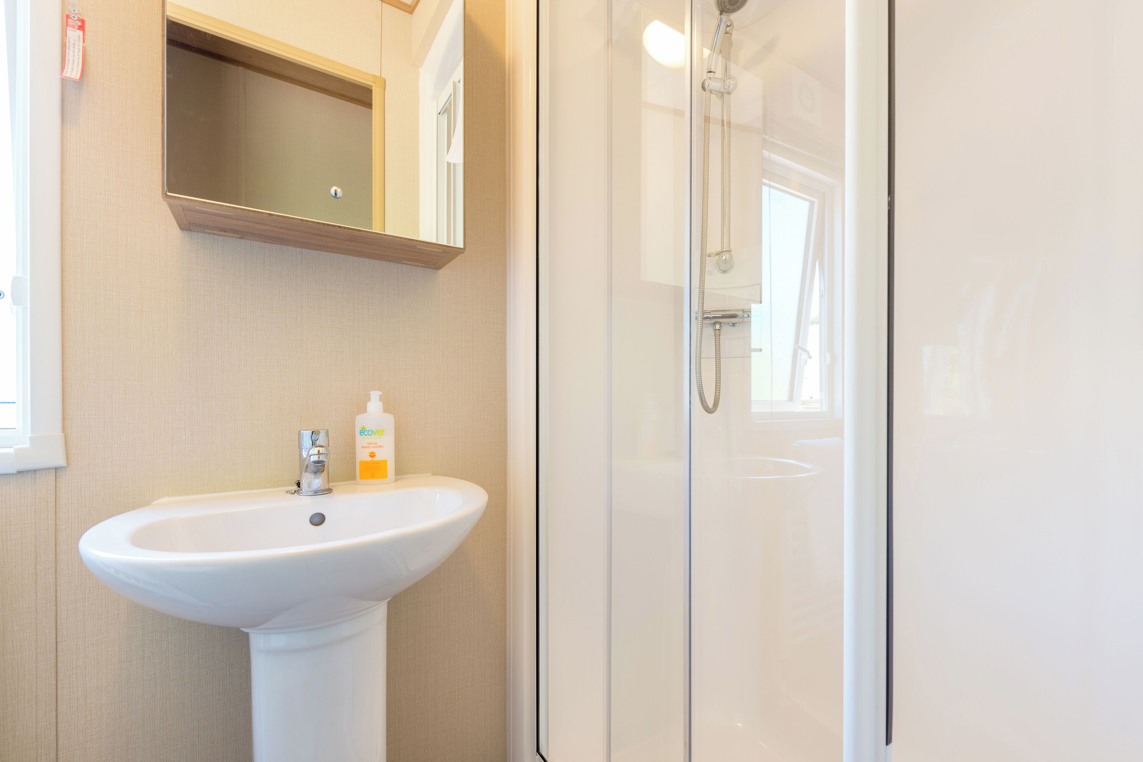 A bathroom with a white sink, a mirror, and a glass-enclosed shower.