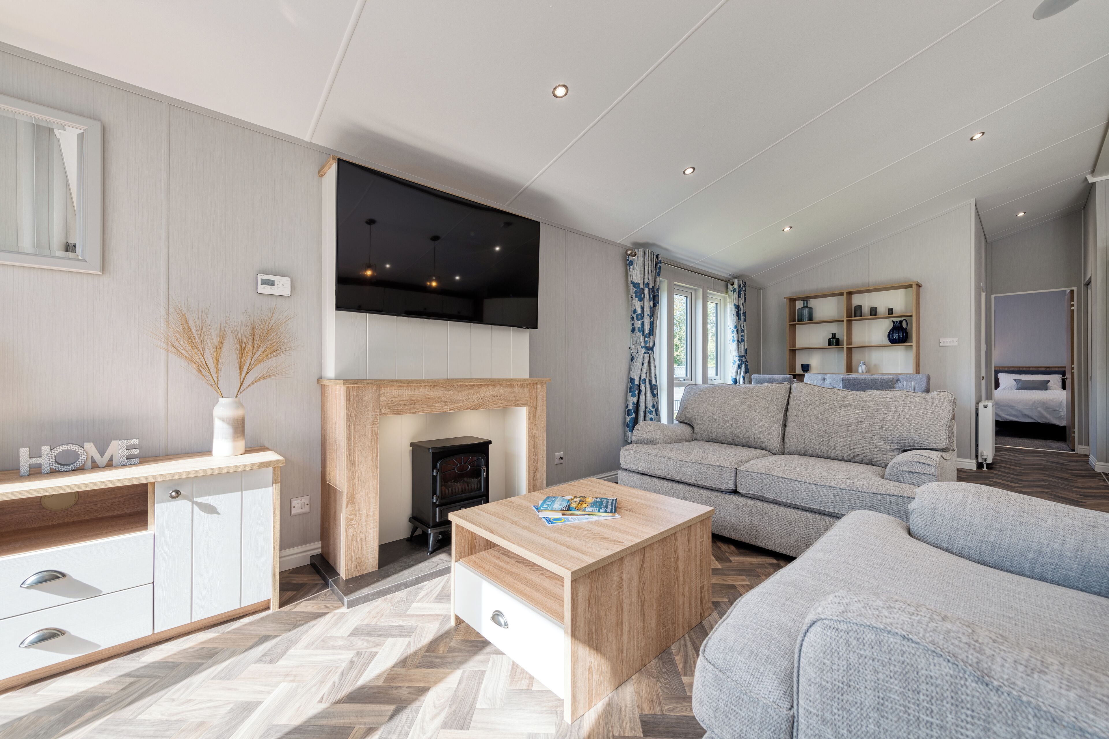Un salon moderne avec une cheminée, un canapé, une table basse et un téléviseur fixé au mur.