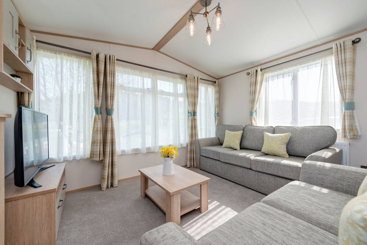 Ein modernes Wohnzimmer mit einer Couch, einem Couchtisch und einem Fernseher auf einer Holzkommode.