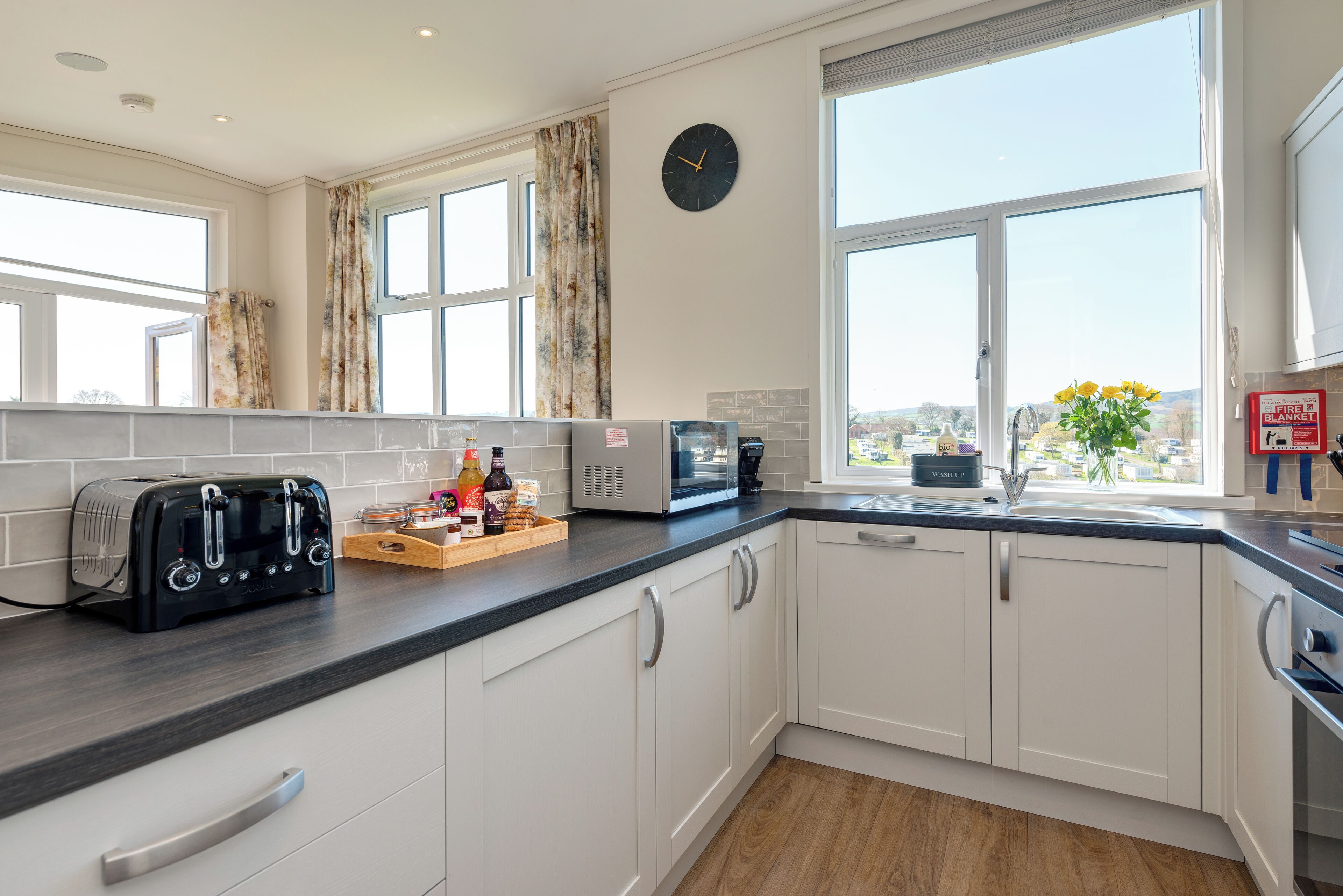 A modern kitchen with white cabinets, a black toaster, a microwave, and a window with a view of the city.