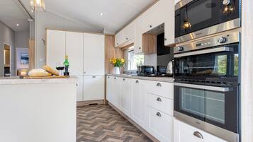 Eine moderne Küche mit weißen Schränken, einem Fischgrätparkett und Edelstahlgeräten, darunter eine Mikrowelle und ein Backofen.