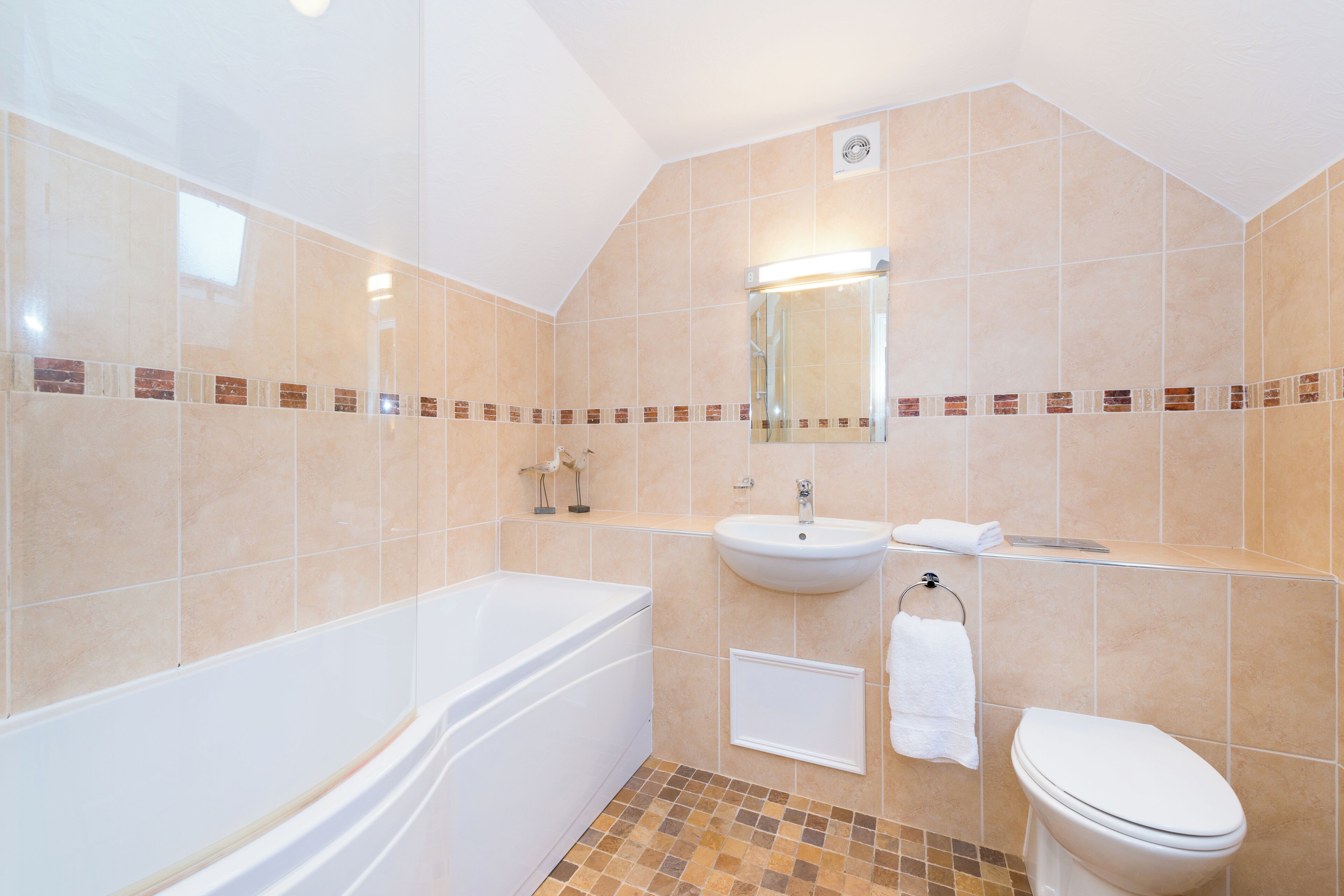 Ein Badezimmer mit Badewanne, Waschbecken und Toilette, gehalten in einer neutralen Farbgebung.