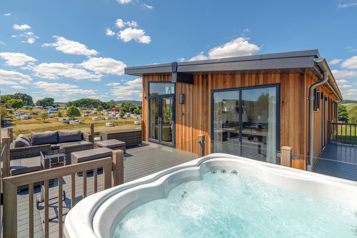 Ein moderner Whirlpool-Bereich im Freien mit Holzboden und Sitzgelegenheiten, mit Blick auf eine schöne Landschaft.