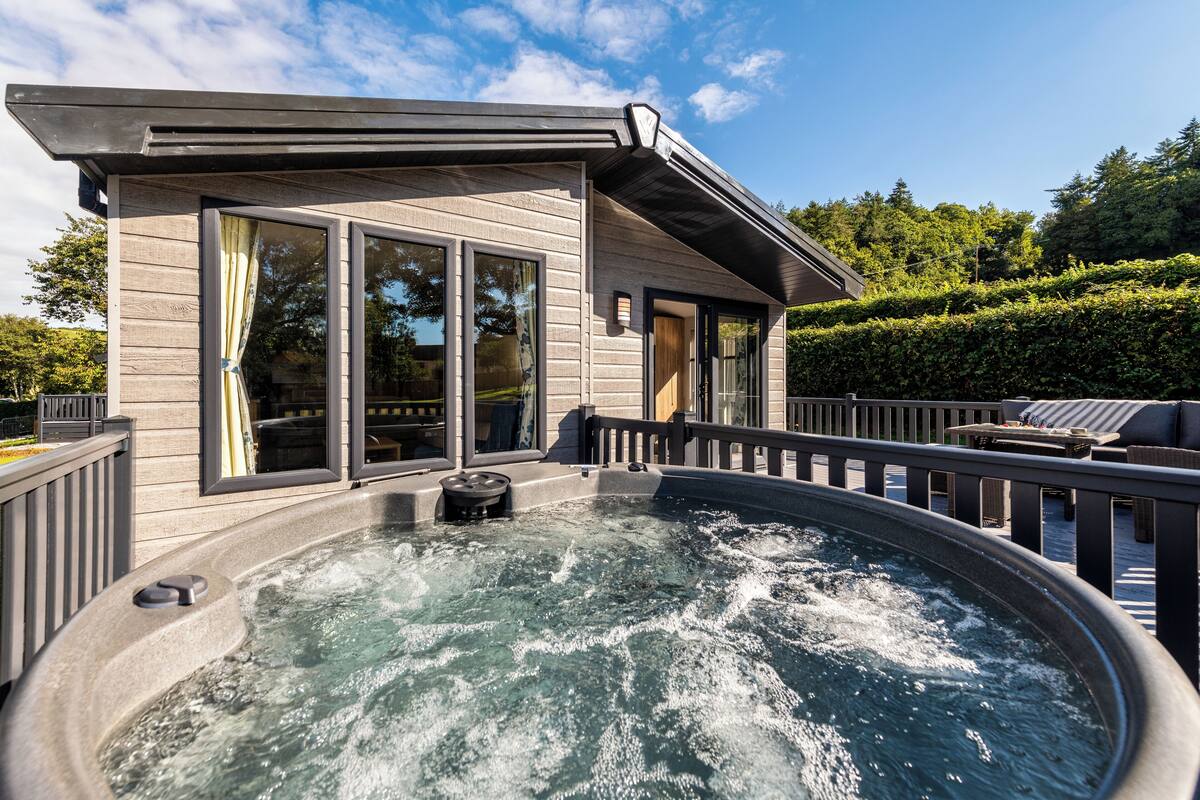 Ein Whirlpool mit einer Holzterrasse und einem Haus im Hintergrund.
