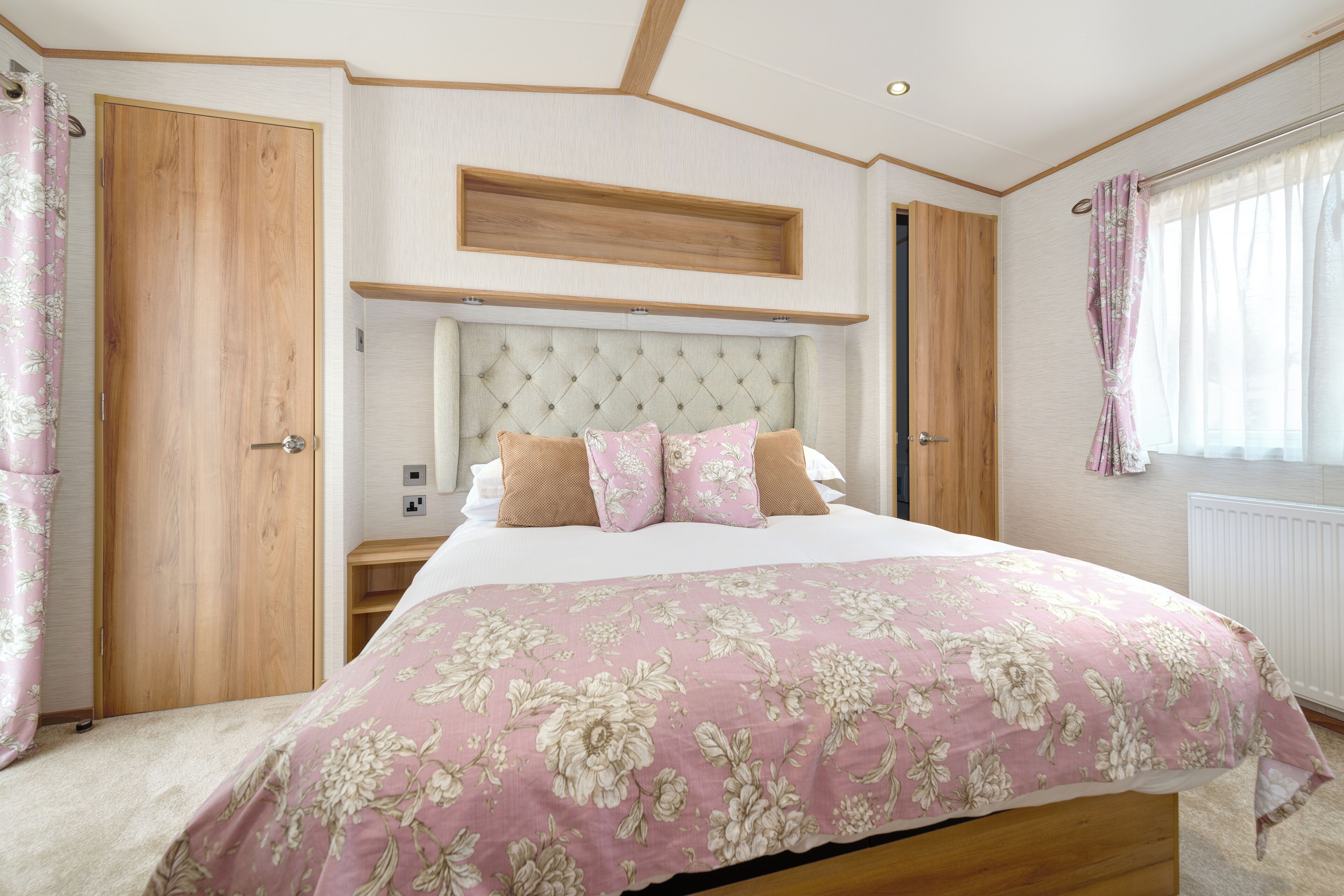 A bedroom with a large bed, wooden headboard, and floral bedding.