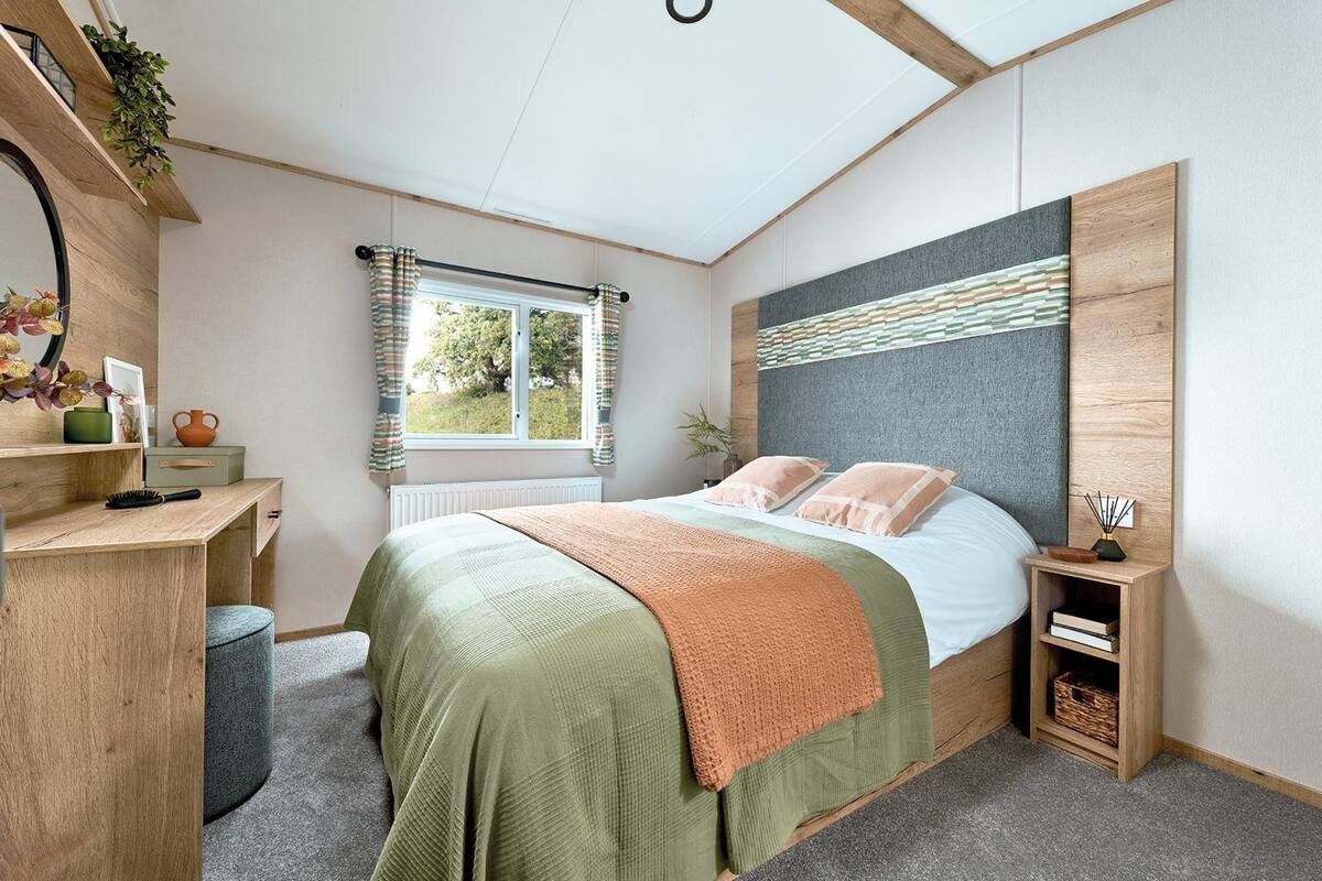 Ein Schlafzimmer mit Bett, Nachttischen, Schreibtisch und Fenster.