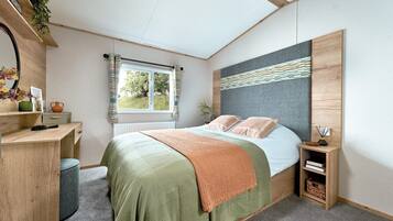 A bedroom with a bed, bedside tables, a desk, and a window.