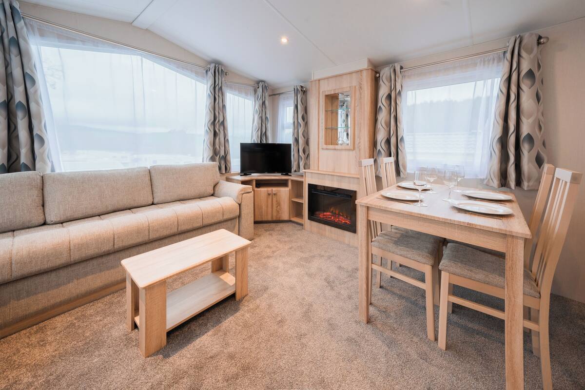 Ein gemütlicher Wohnbereich mit Sofa, Fernseher, Kamin und Esstisch für zwei Personen.