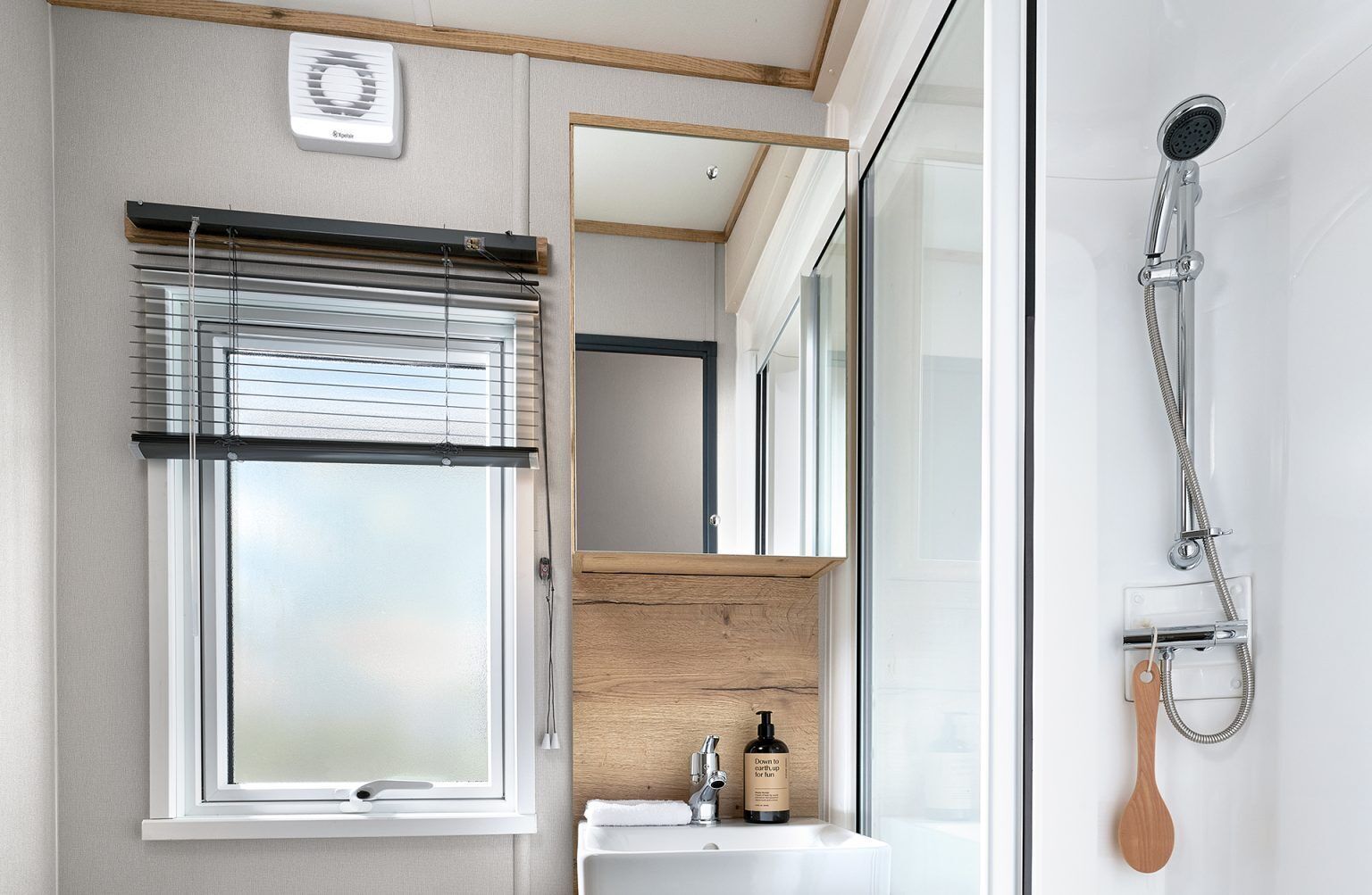 A modern bathroom with a large window, a shower, and a wooden vanity.
