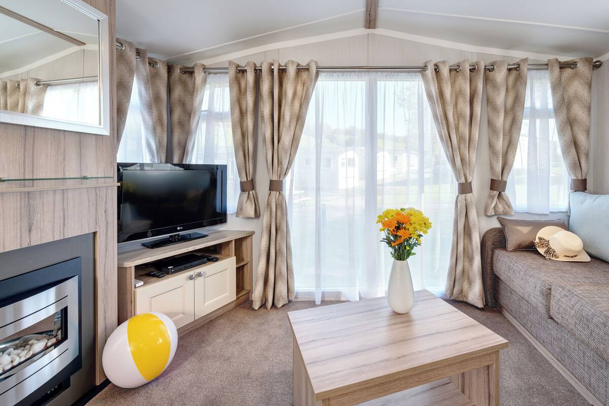 Ein modernes Wohnzimmer mit Flachbildfernseher, Kamin, Sofa und Couchtisch.