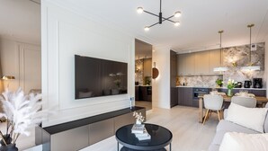 Uma sala de estar moderna com uma televisão de tela plana, uma mesa de centro preta e um sofá.