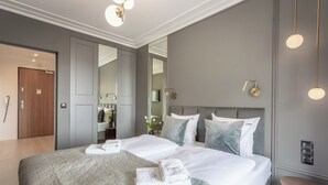 Quarto de hotel moderno com uma cama grande, mesa de cabeceira, espelho e guarda-roupa.