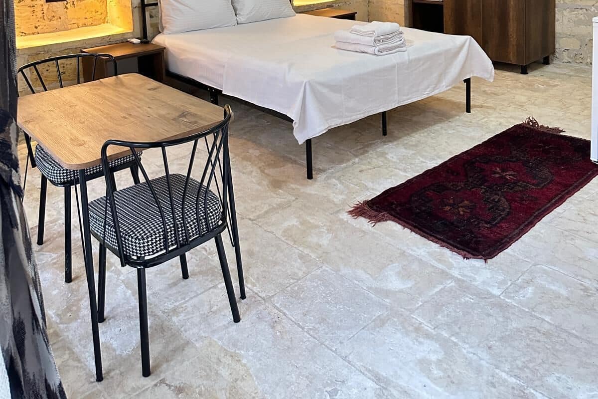 A room with a bed, a table, chairs, and a wardrobe.