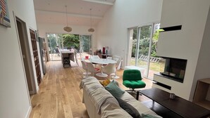 Et moderne interiør med lang trægulv, en sofa, et spiseområde med bord og stole, samt et fjernsyn på et stativ.