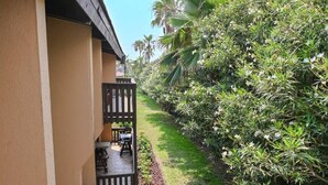 Un balcón con vistas a un jardín cuidado y la fachada de un edificio.