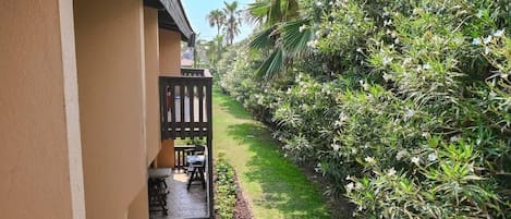 A balcony with a view of a well-maintained garden and a building facade.